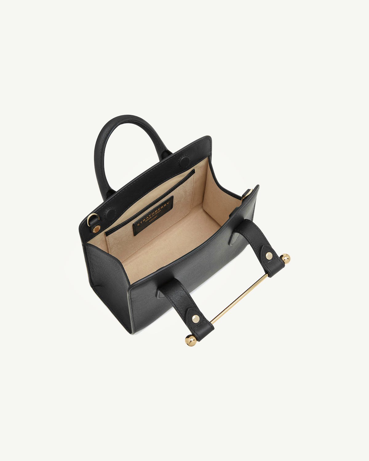 Black Strathberry nano tote open showing beige interior and gold bar