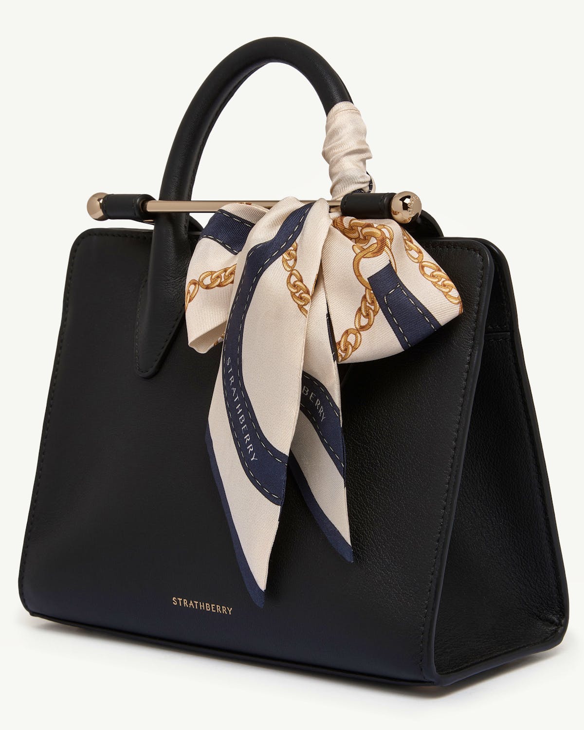 Black Strathberry bag with navy and vanilla belt-print silk skinny scarf tied to handle