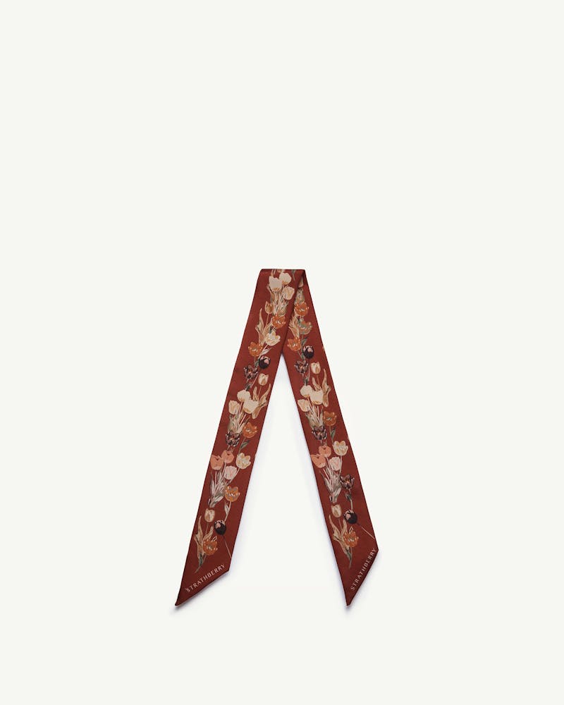 Strathberry silk skinny scarf, oxblood tulip print, arranged in a V shape.