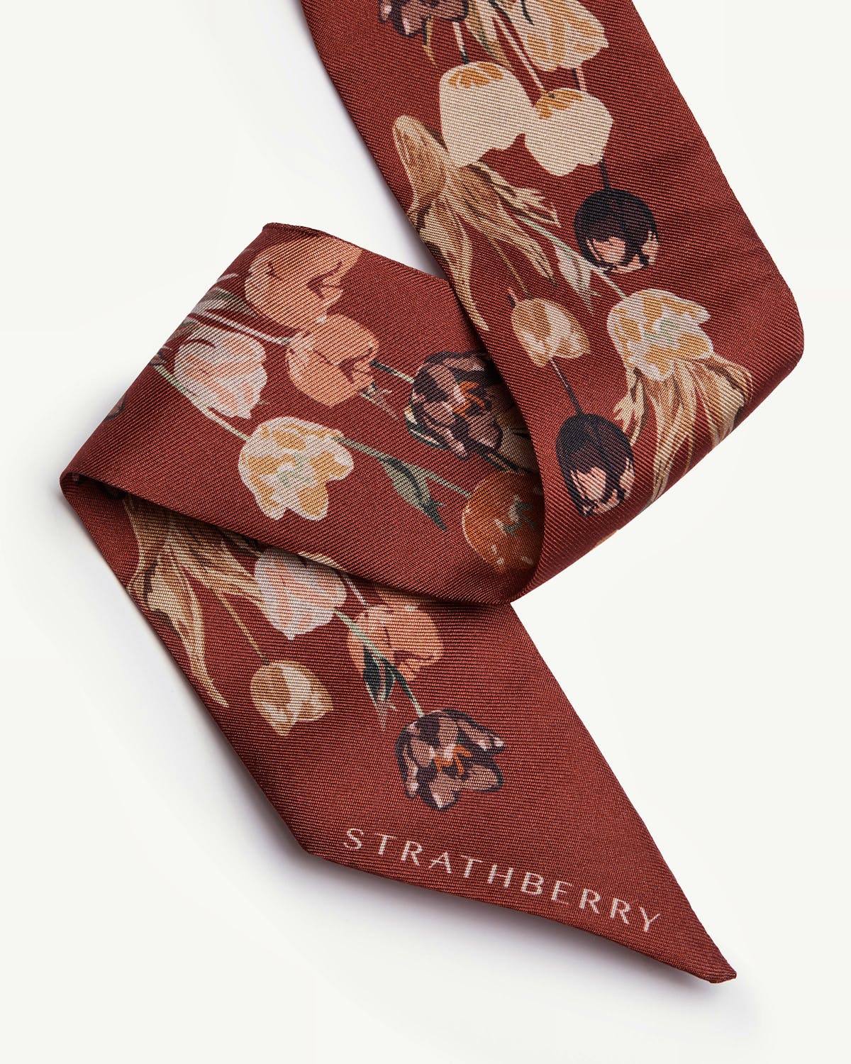 Folded oxblood silk skinny scarf with tulip print and Strathberry wordmark.