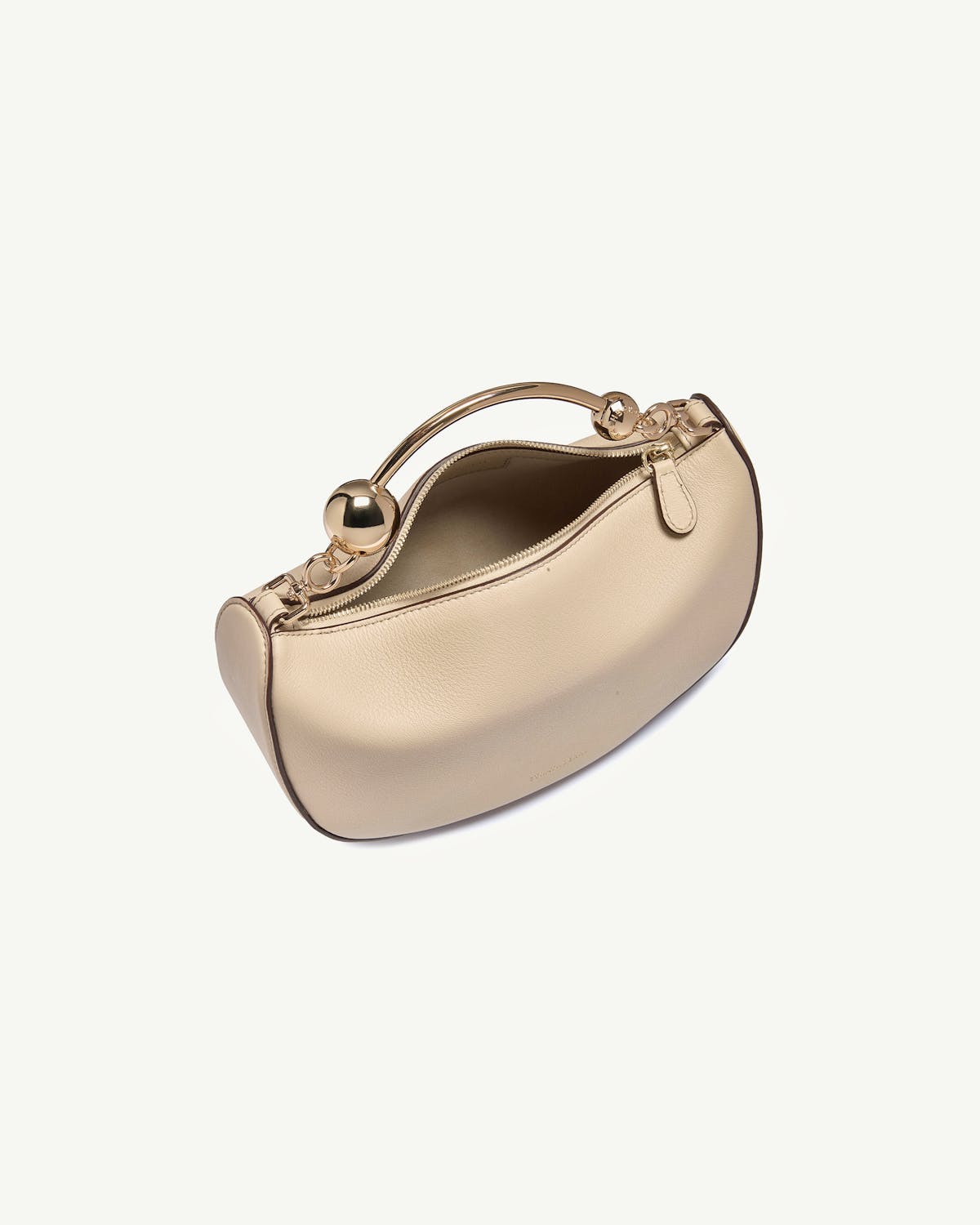 Oat crescent mini bag with gold ball handle, top zip partially open.
