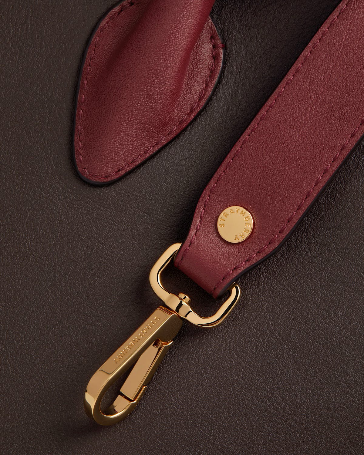 Strathberry tote strap in oxblood with gold clasp on espresso leather