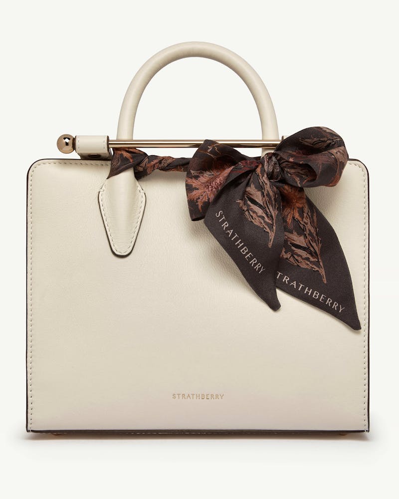 Espresso thistle silk skinny scarf tied to white Strathberry leather handbag.