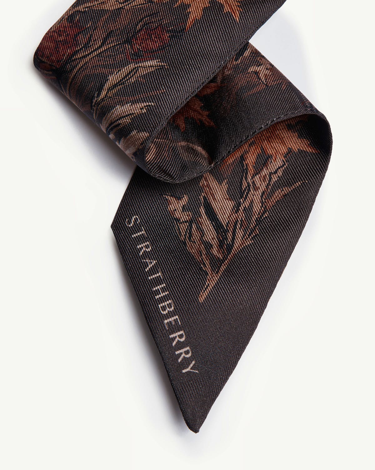 Espresso thistle print silk skinny scarf tip with visible Strathberry logo.