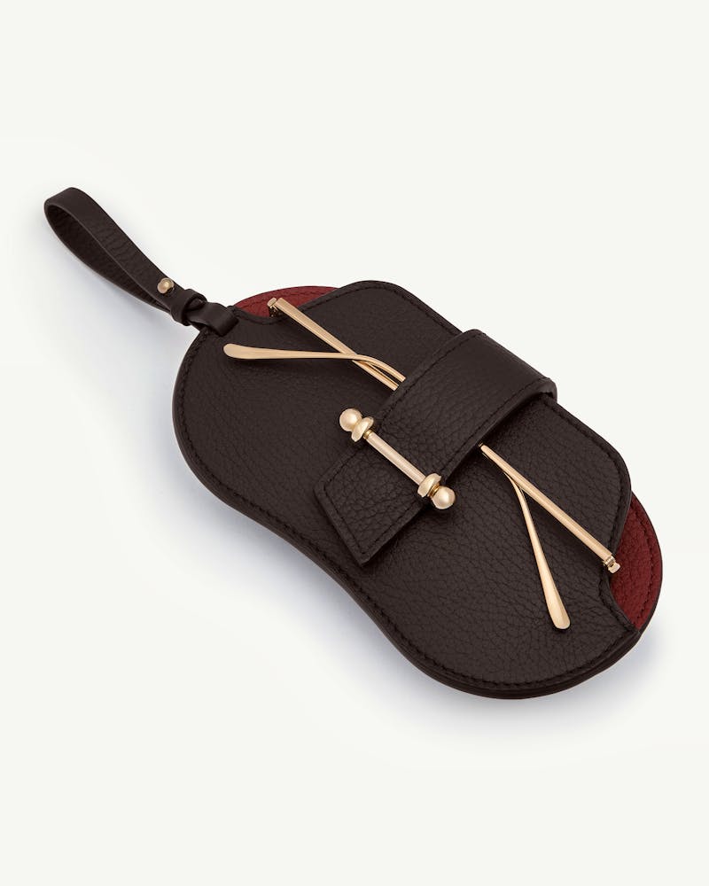 Espresso and oxblood leather sunglasses case with gold-tone bar detail and wrist strap.