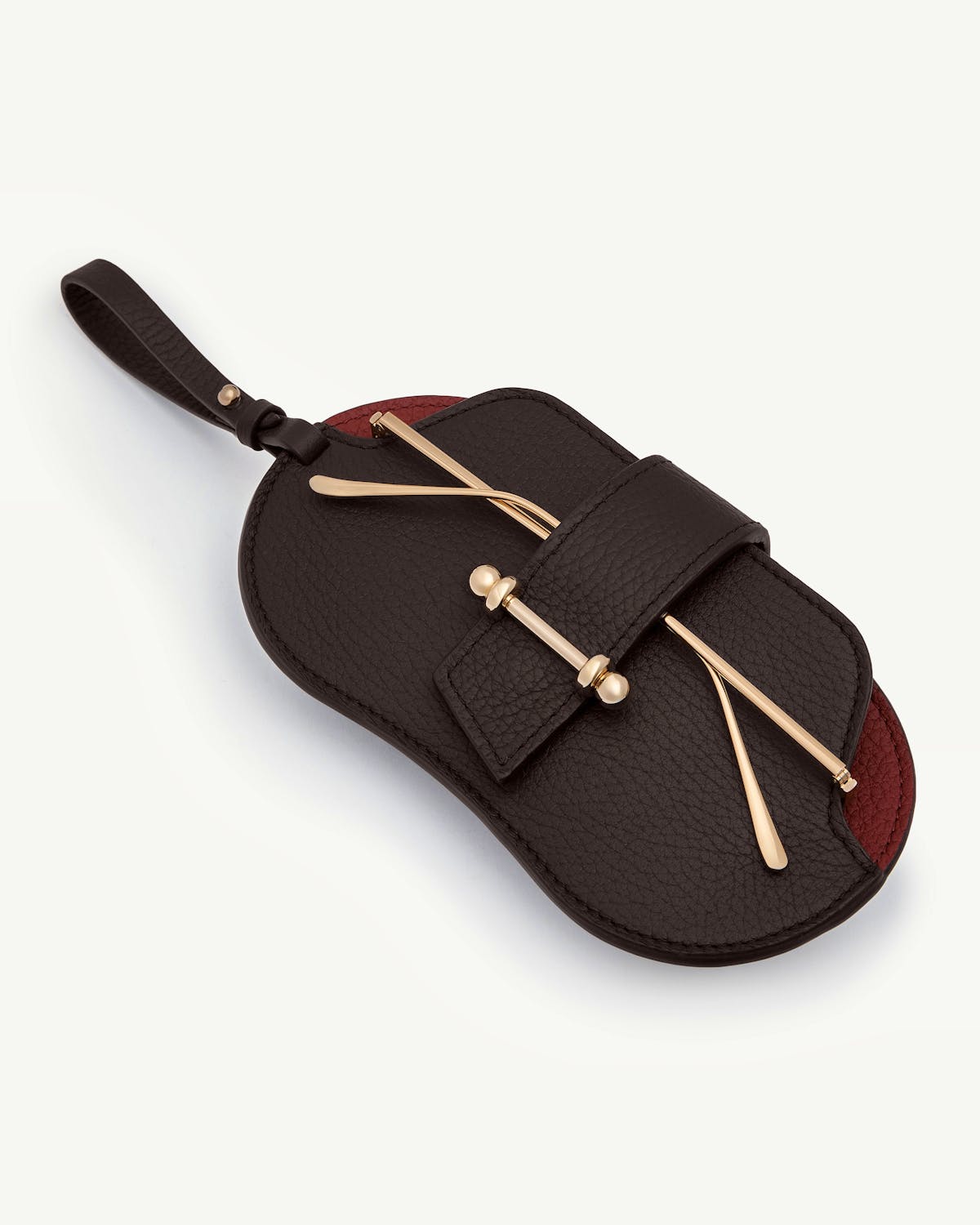 Espresso and oxblood leather sunglasses case with gold-tone bar detail and wrist strap.