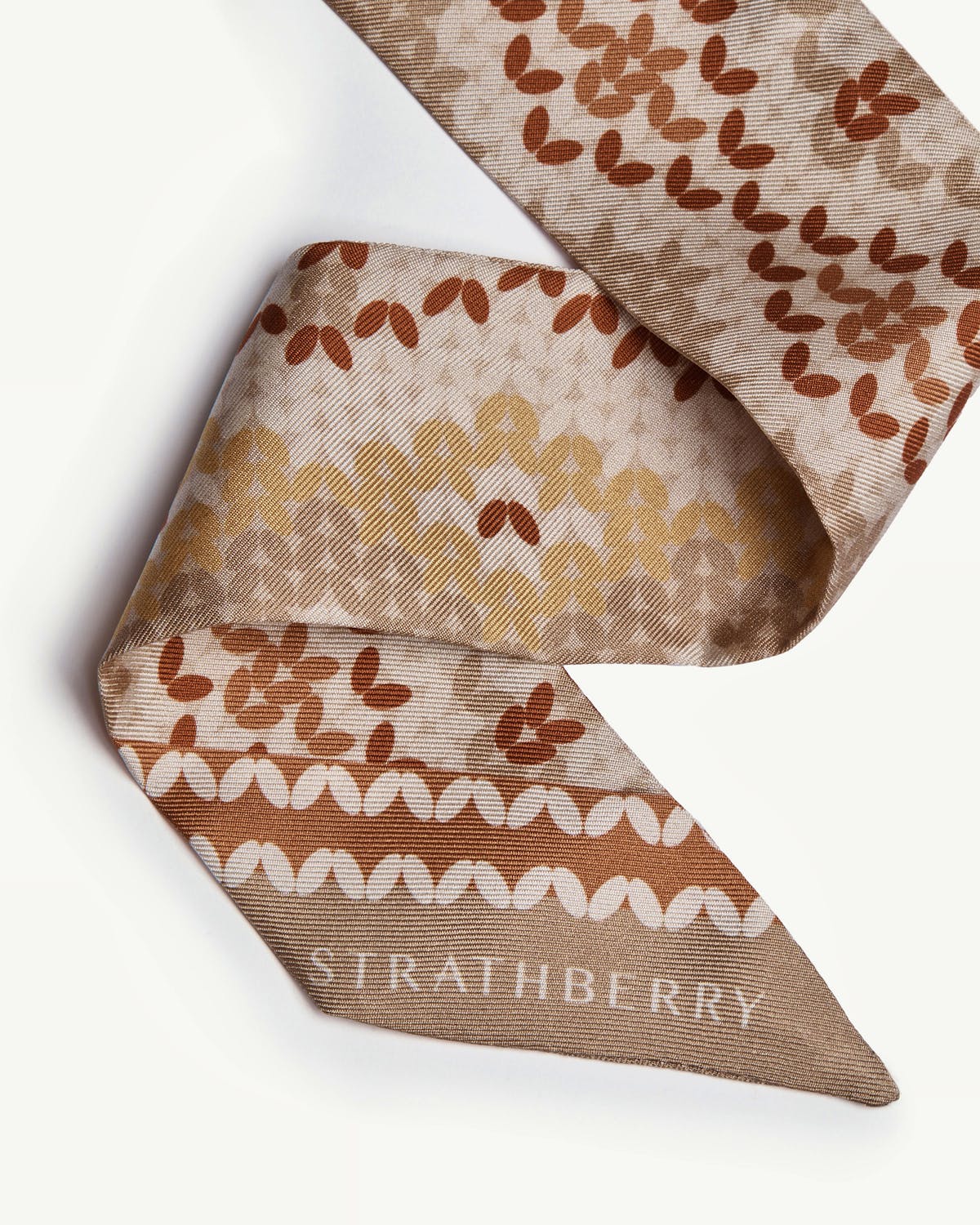 Brûlée Fair Isle silk skinny scarf folded, repeating motif and Strathberry logo.
