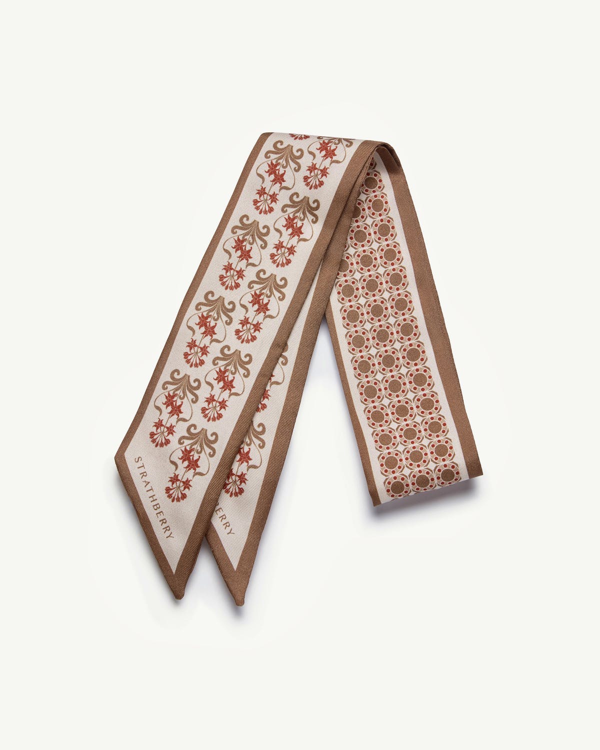 Tan silk skinny scarf with geometric and floral print, Strathberry logo at end.