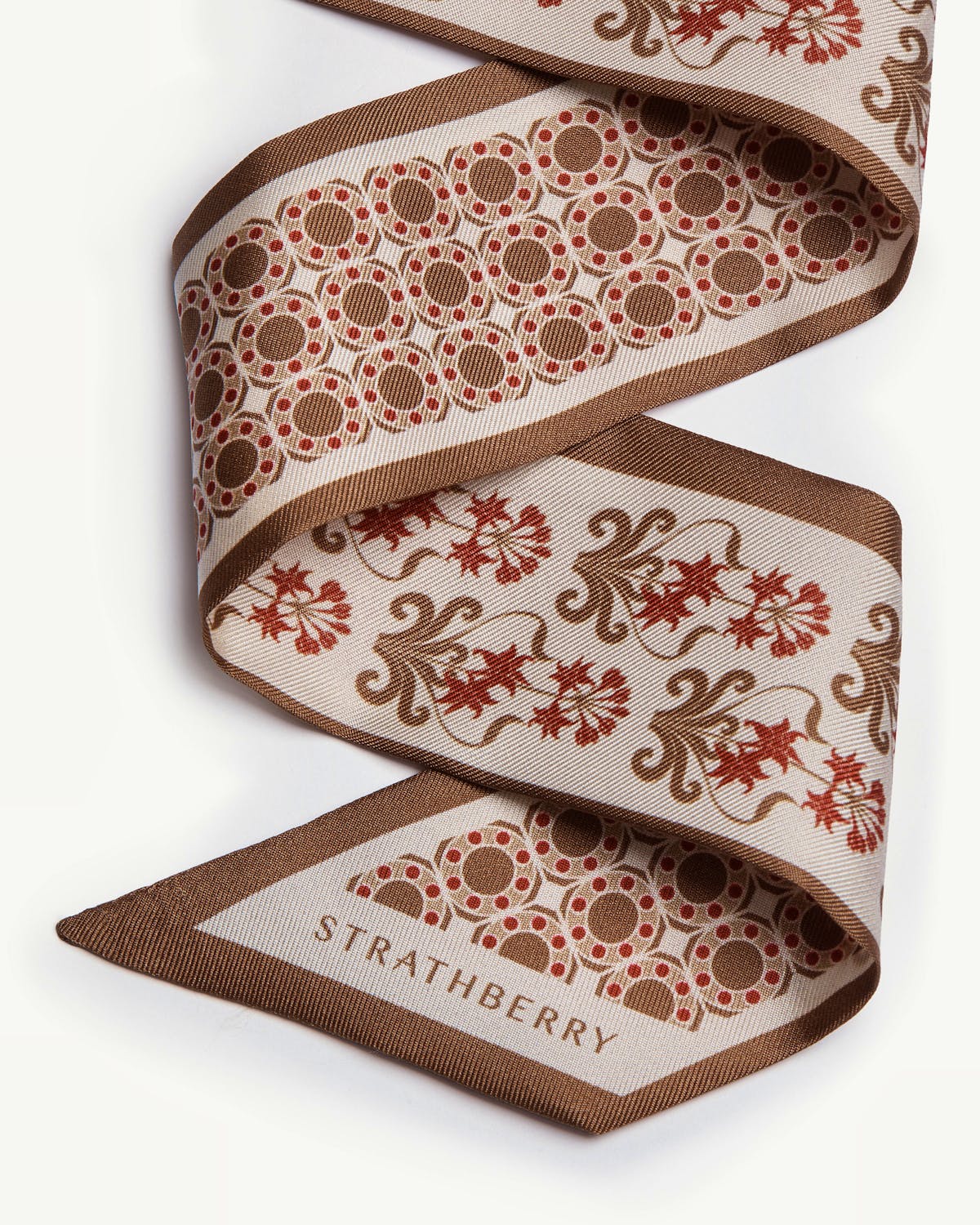 Tan geometric print silk skinny scarf with Strathberry name printed on tip.