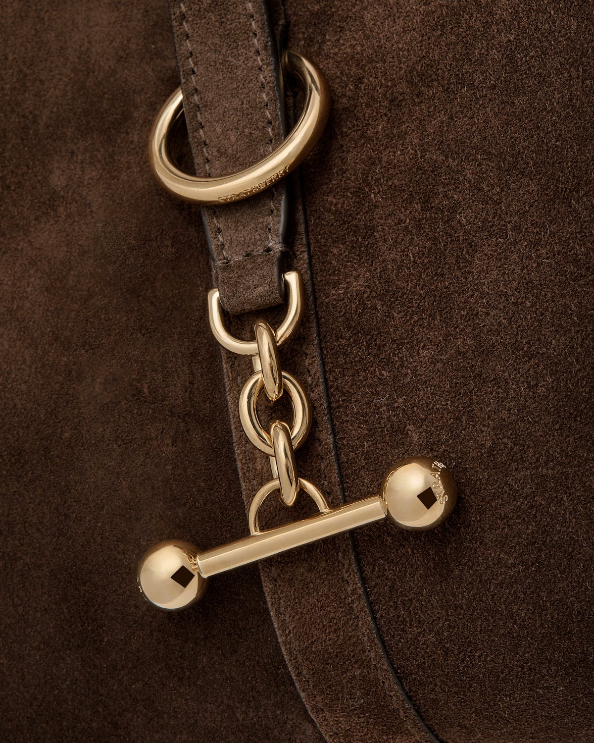 Chocolate suede bag hardware with gold toggle bar, chain and strap by Strathberry.