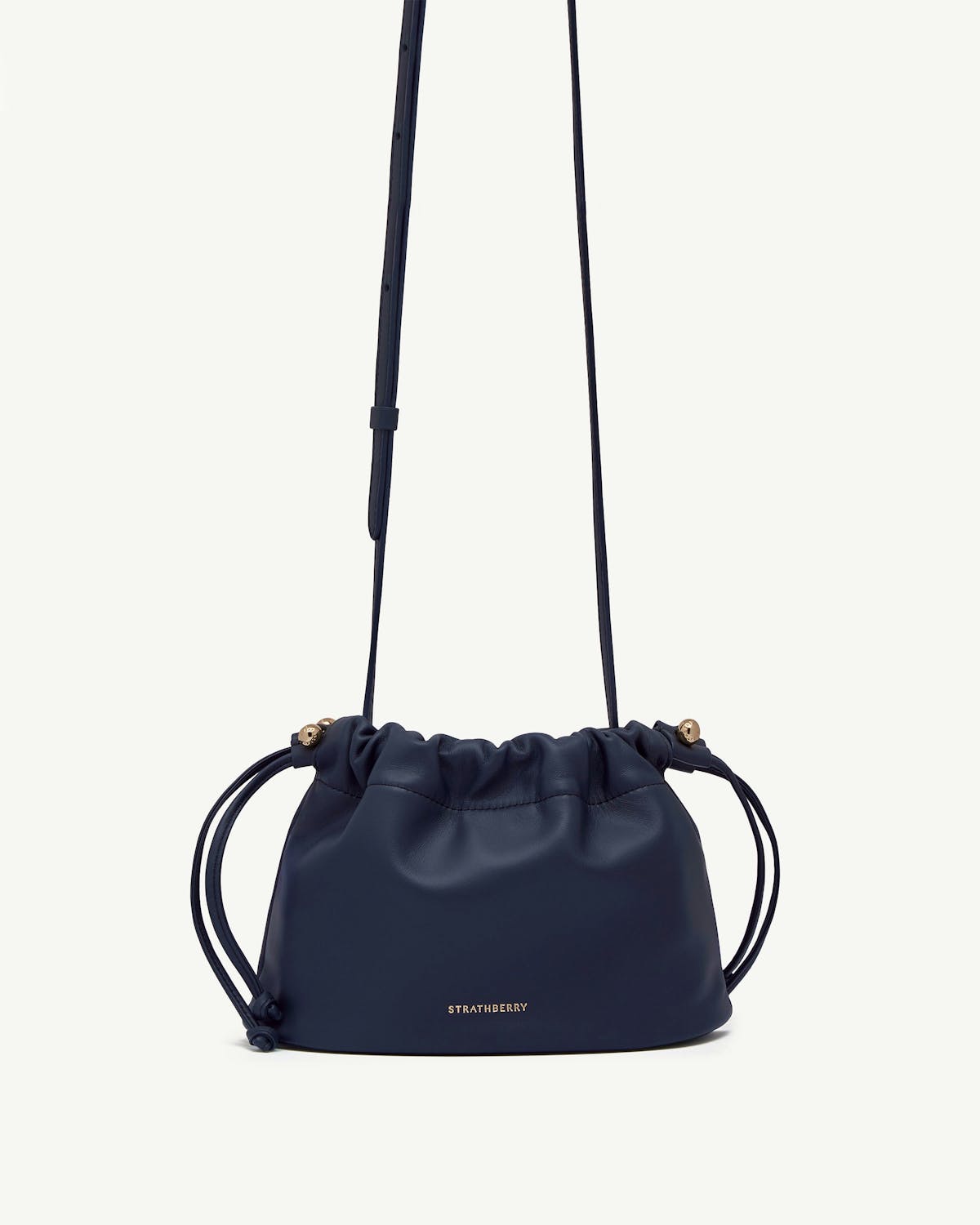 Marine blue Charlotte drawstring bag with long strap, gold hardware, Strathberry logo.