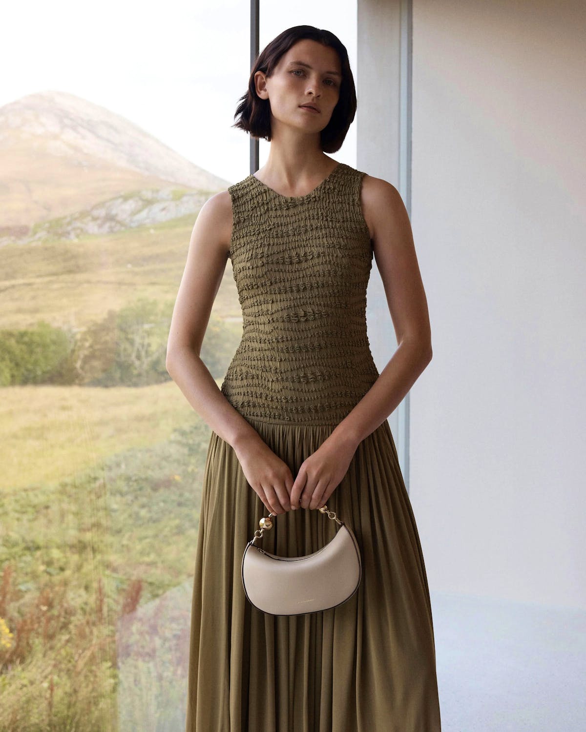 Model holding oat crescent moon mini handbag with gold chain handle