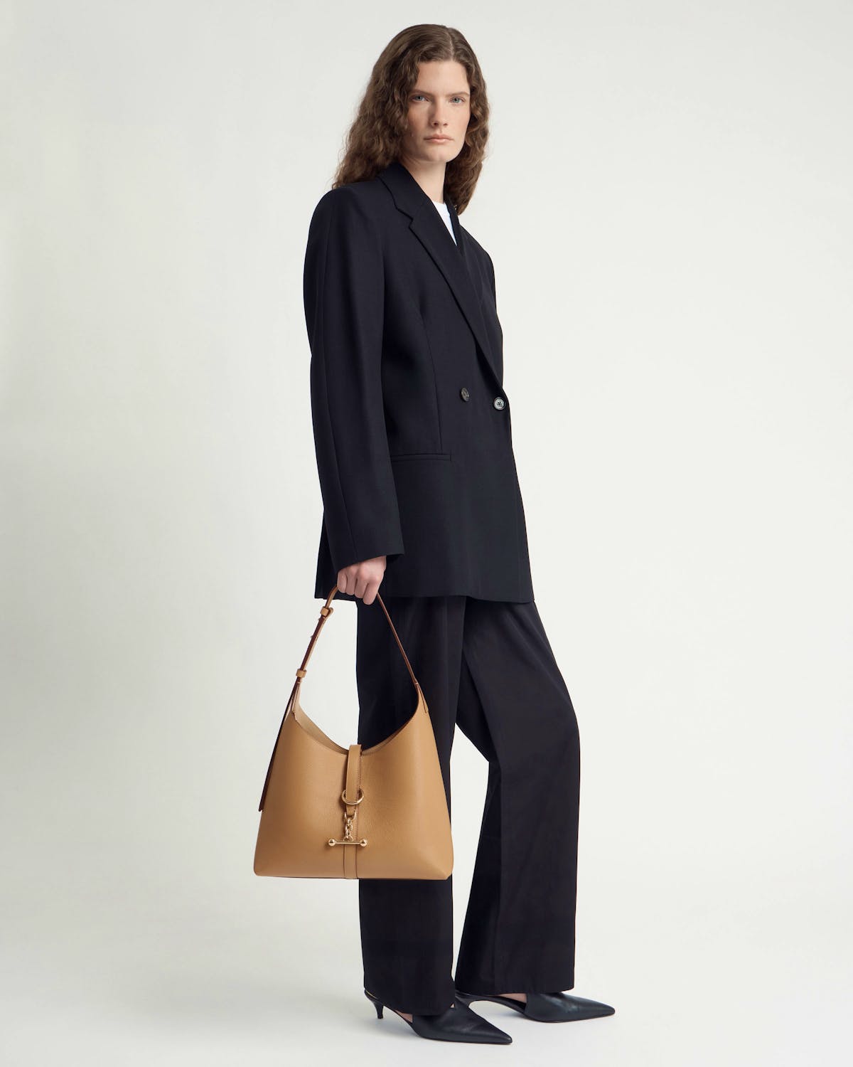 Model holding a caramel leather Kite Hobo bag with gold hardware.