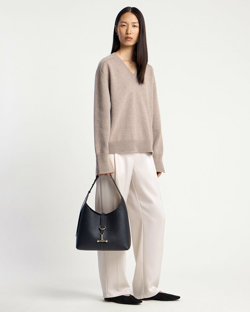 Model holding a black Kite Hobo bag with gold hardware and strap.