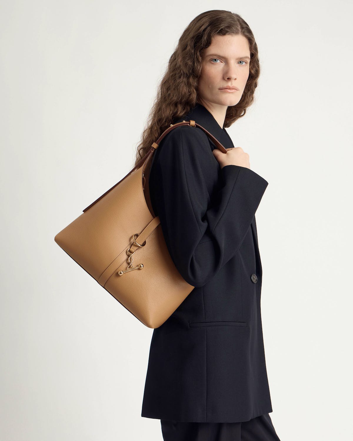 Model wearing a caramel leather Kite Hobo bag on her shoulder.