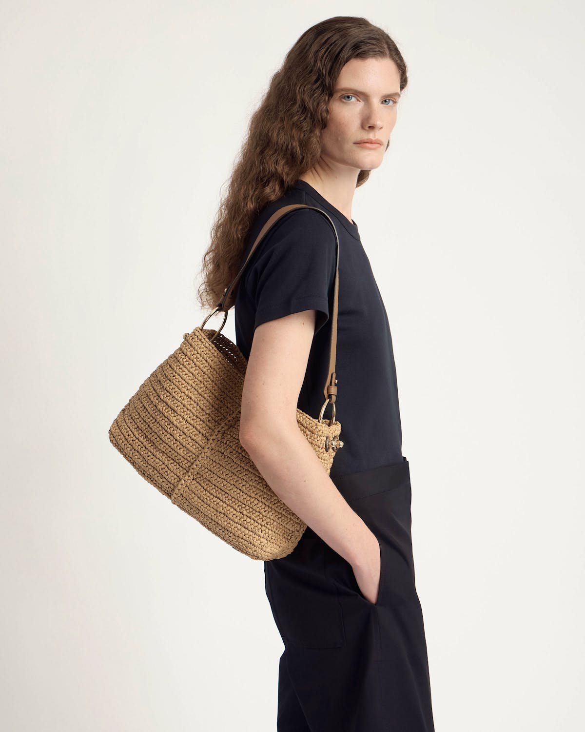 Model wearing a raffia and clay hobo bag over her shoulder.