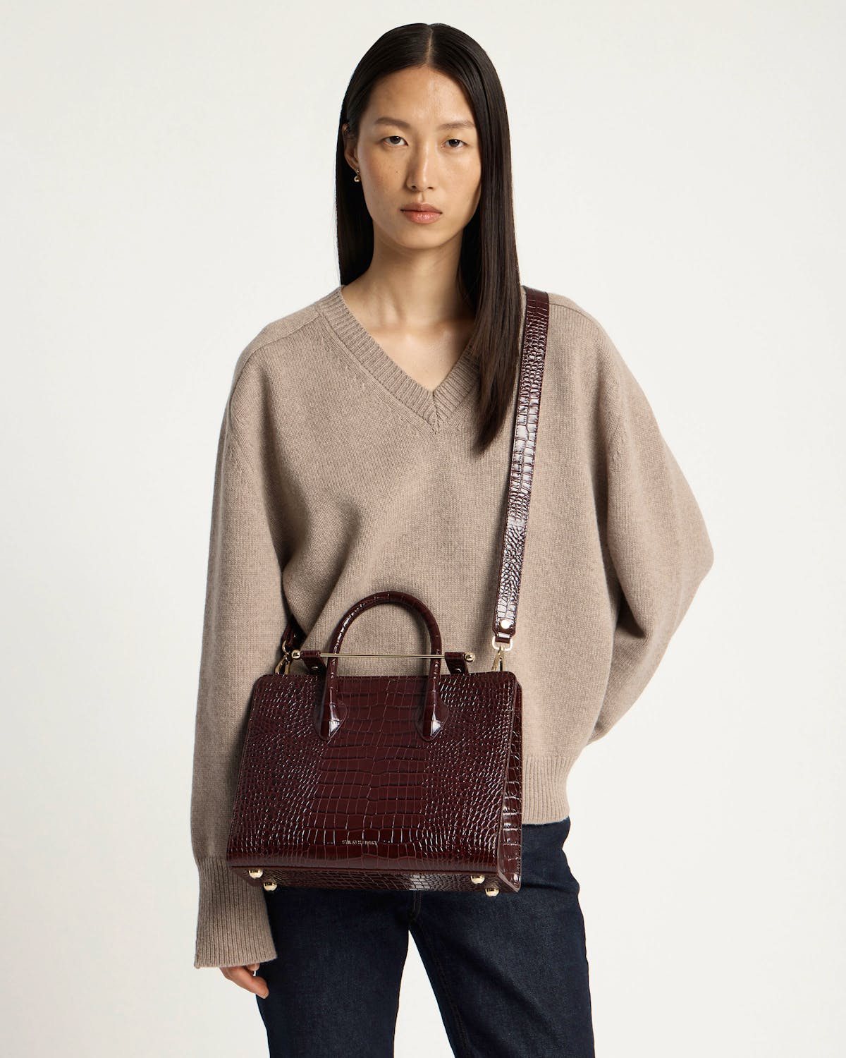Model wearing a croc-embossed midi tote with long shoulder strap.