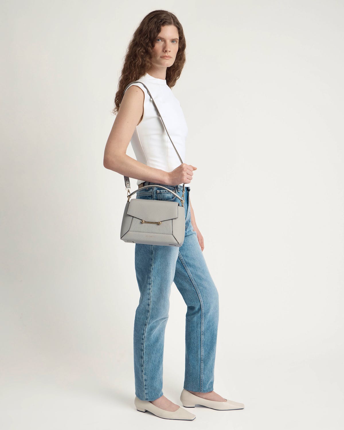 Model wearing white top and jeans, carrying a marble grey mosaic crossbody bag.