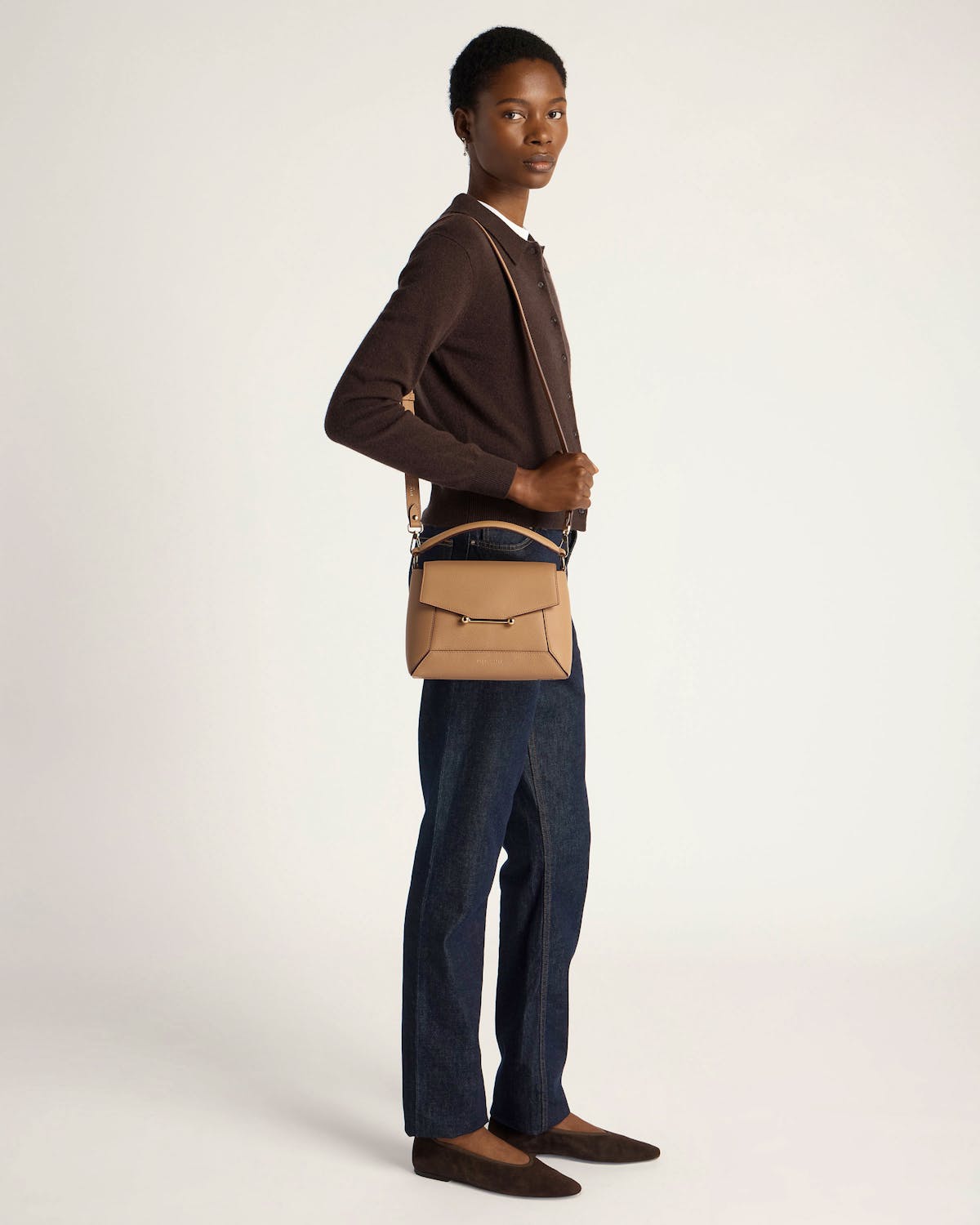 Model wearing a caramel mosaic crossbody bag with brown cardigan and dark jeans.