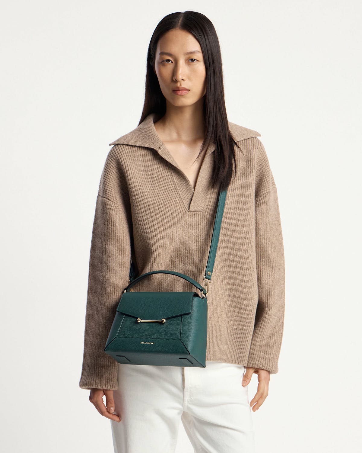 Model wearing Strathberry bottle green mosaic bag with top handle, shoulder strap, and gold bar.
