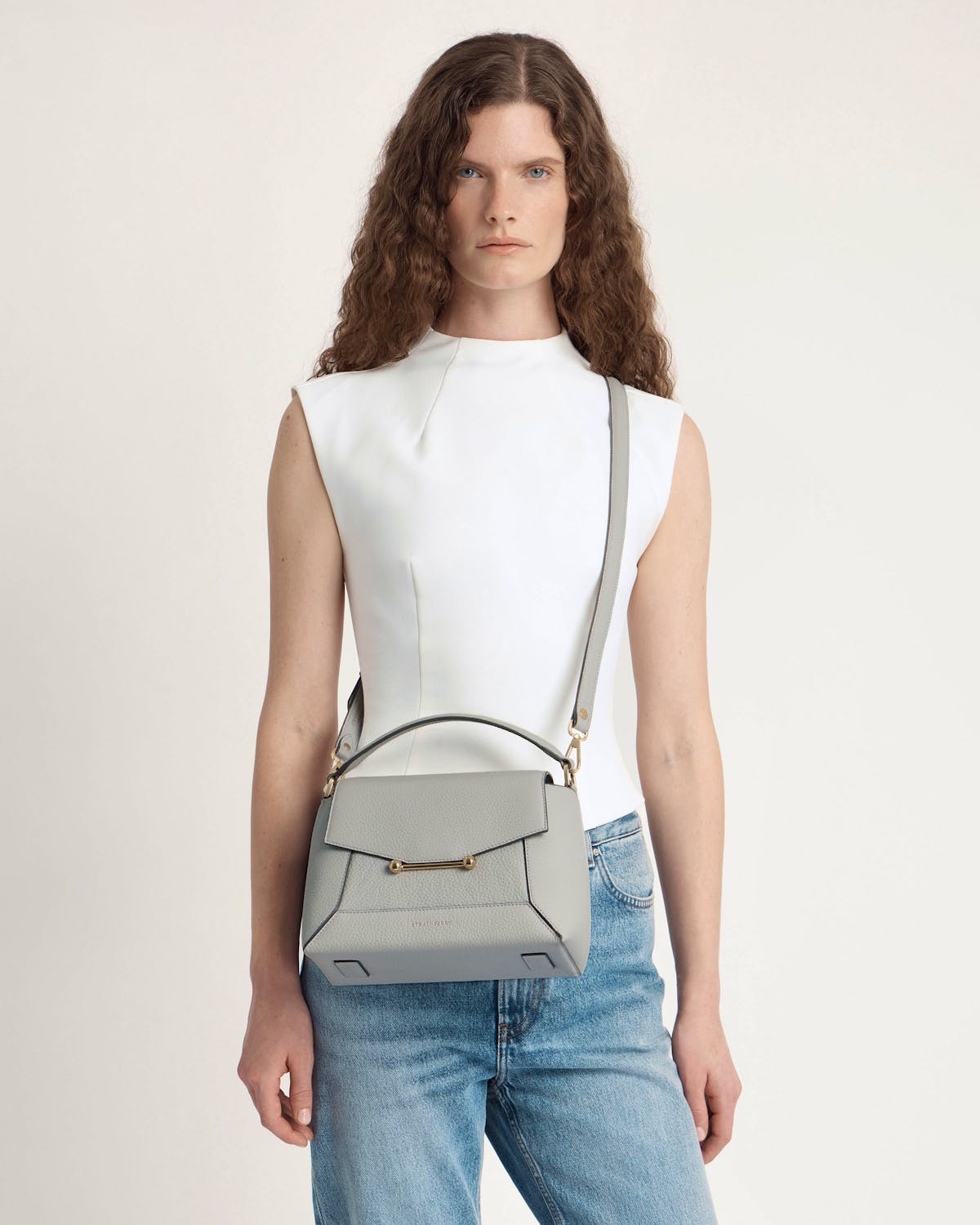 Model wearing marble grey Strathberry mosaic bag with top handle and crossbody strap.