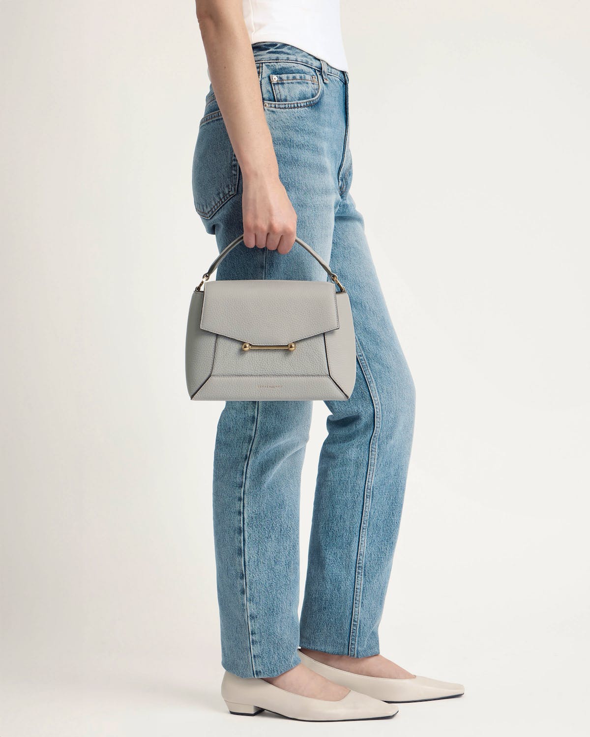 Model holding marble grey mosaic bag by top handle, wearing jeans and flats.