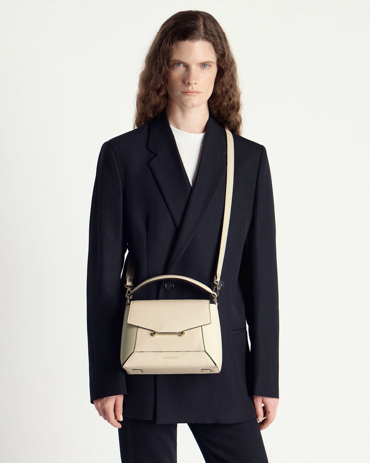 Model wearing black blazer with a vanilla Strathberry mosaic bag worn crossbody.
