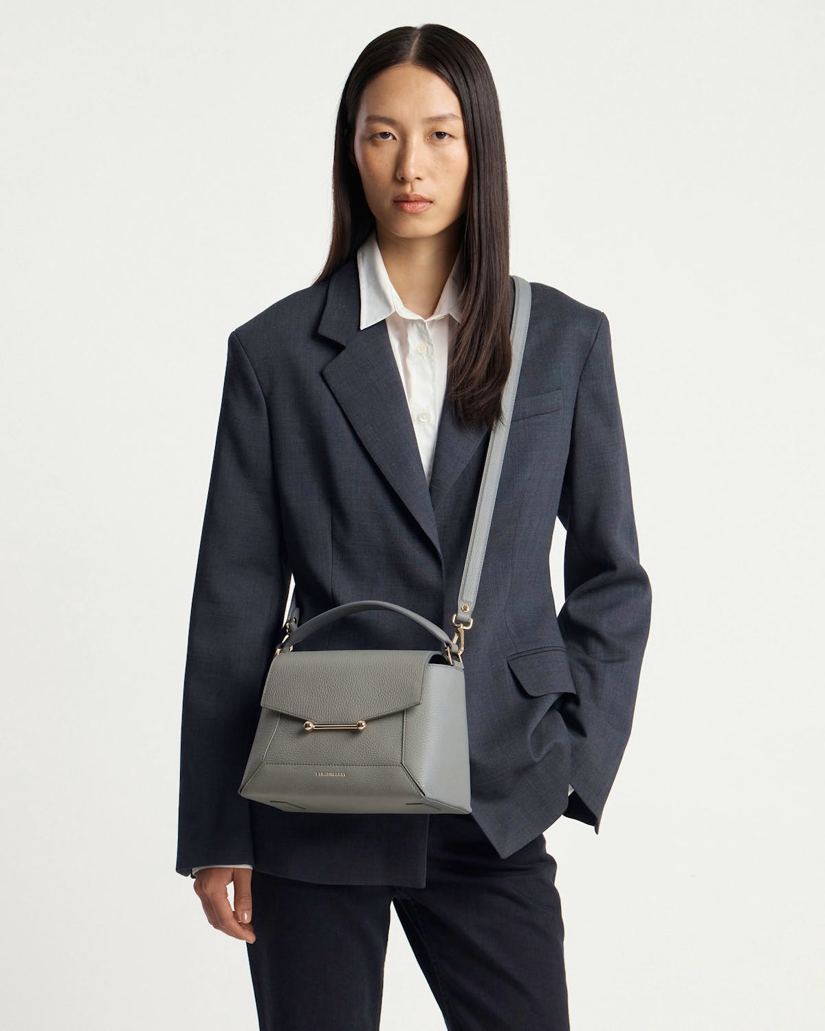 Model wearing stone grey Mosaic bag with top handle and shoulder strap.