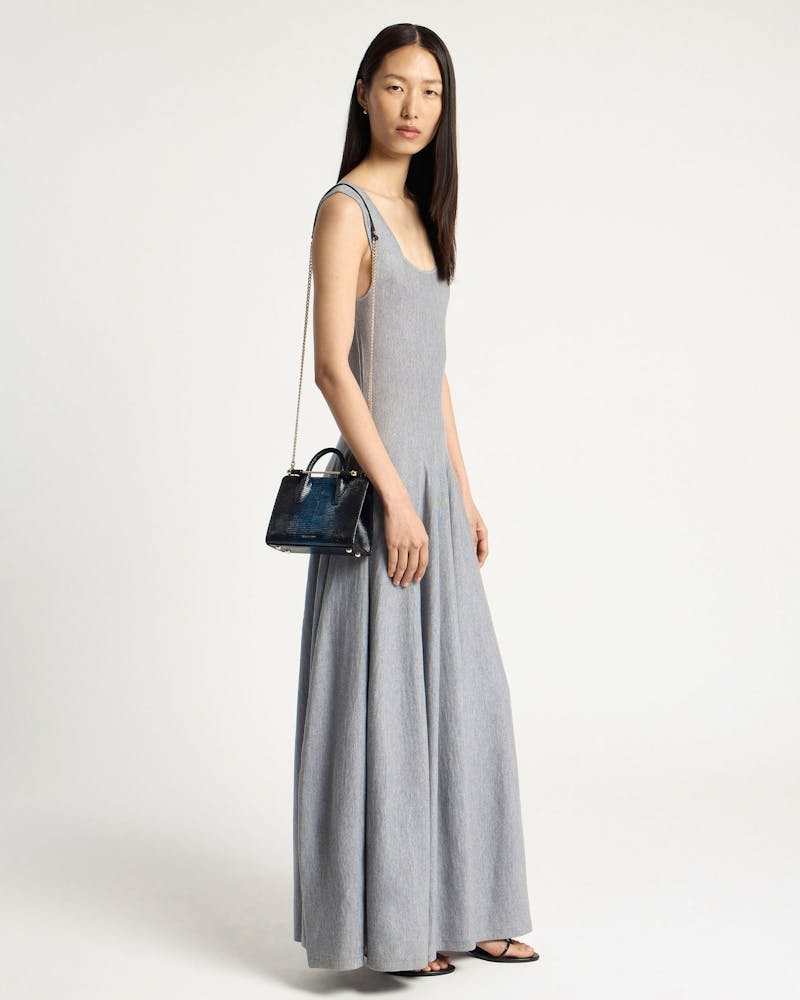 Model in grey maxi dress holding a lizard-effect nano tote with chain strap