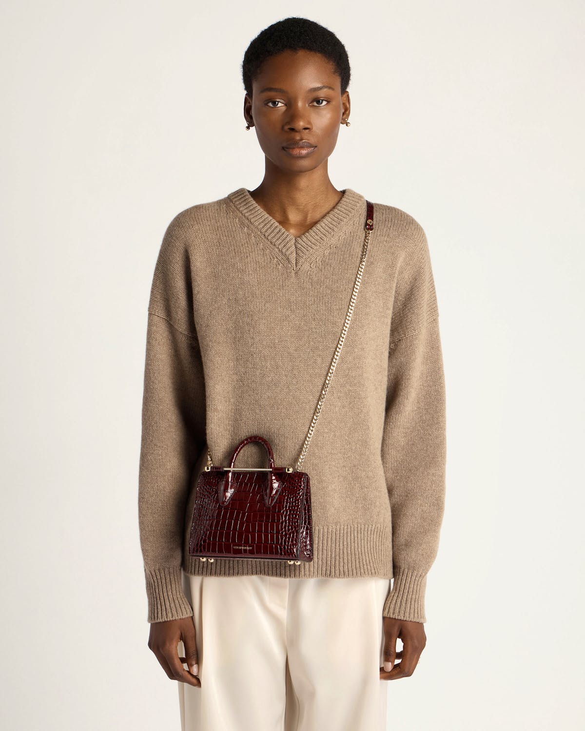 Model wearing dark red croc nano tote with gold chain crossbody strap.