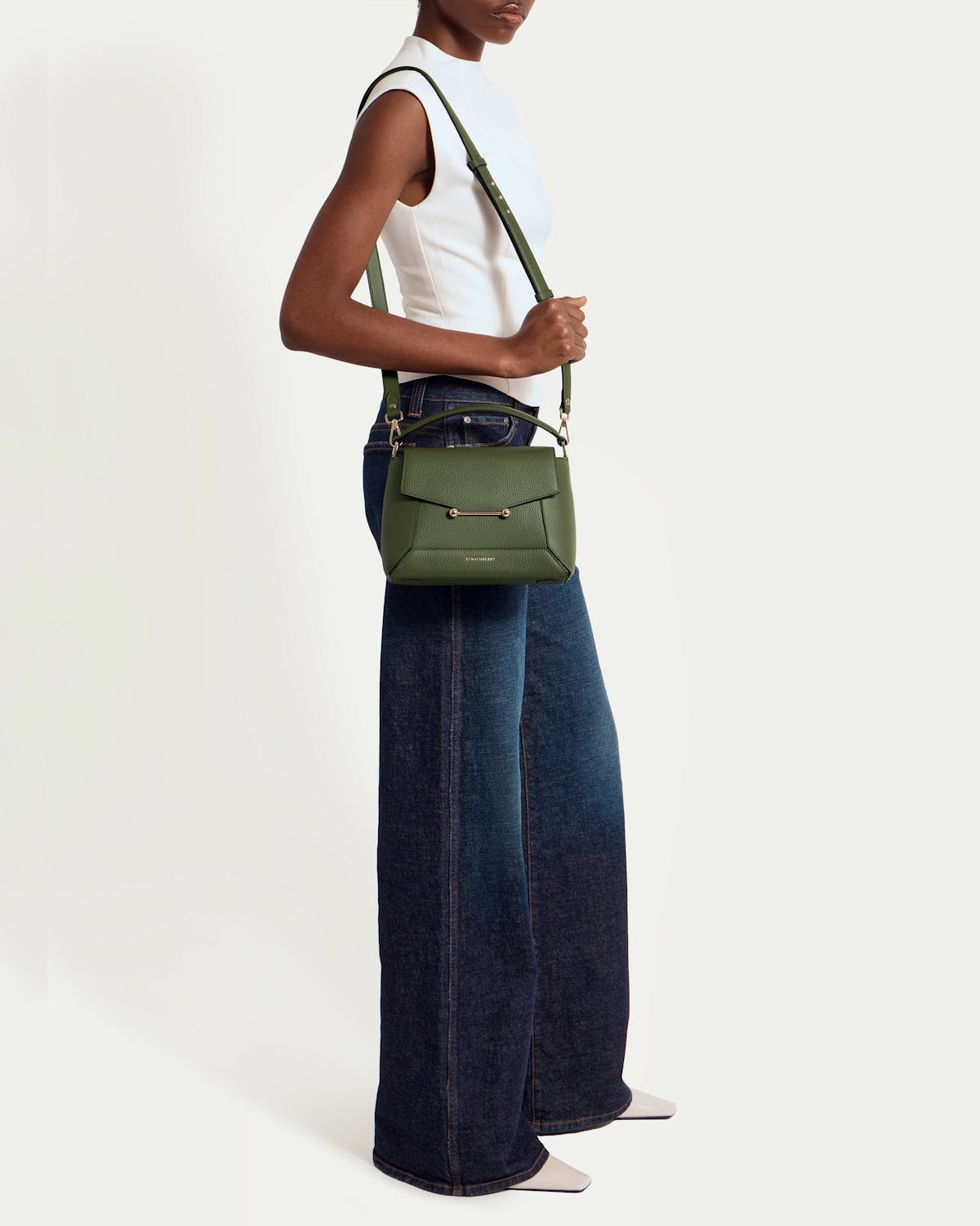 Model wearing a white sleeveless top and wide-leg jeans carrying pine green Mosaic bag.