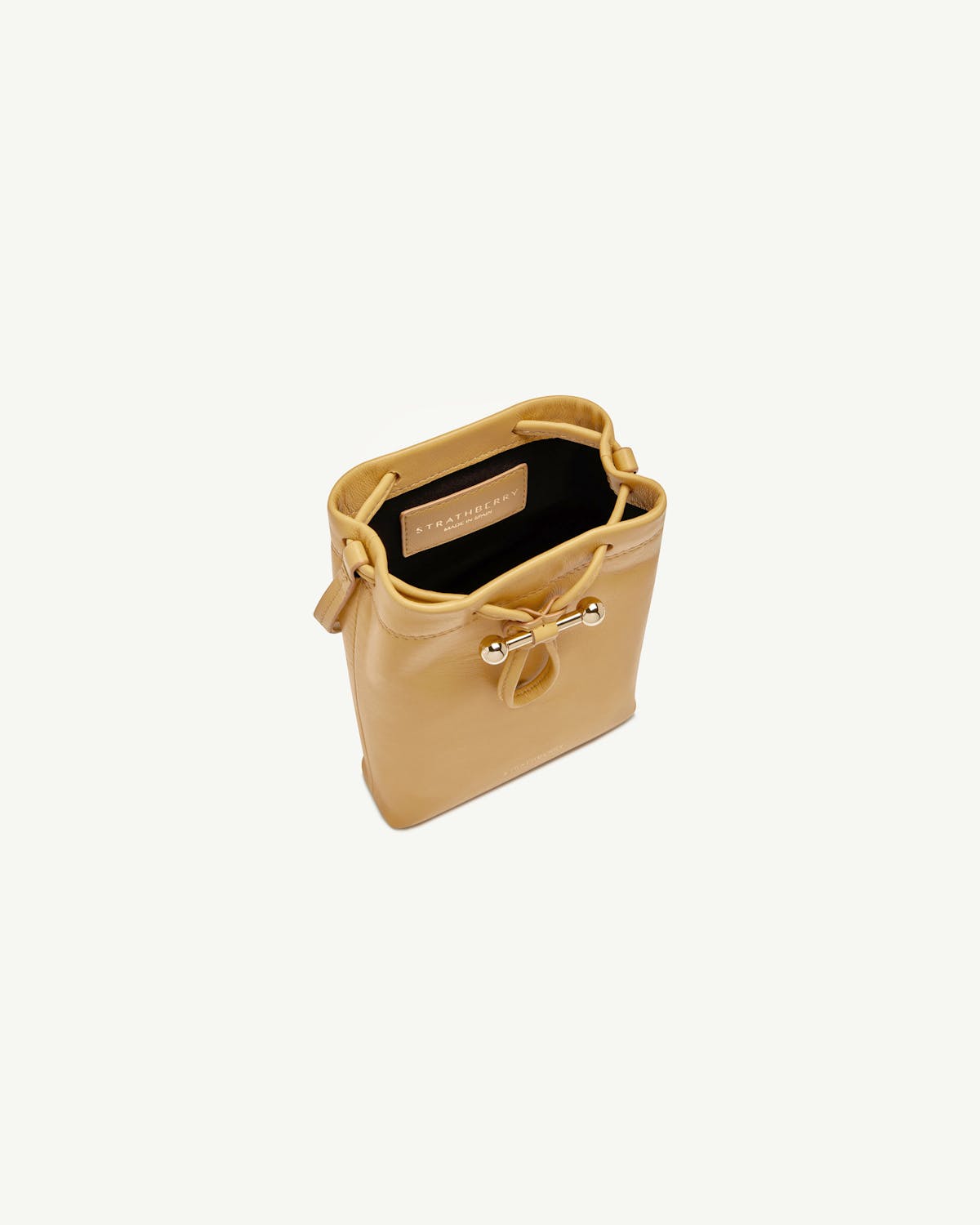 Strathberry Osette midi pouch in brûlée leather with gold bar detail.