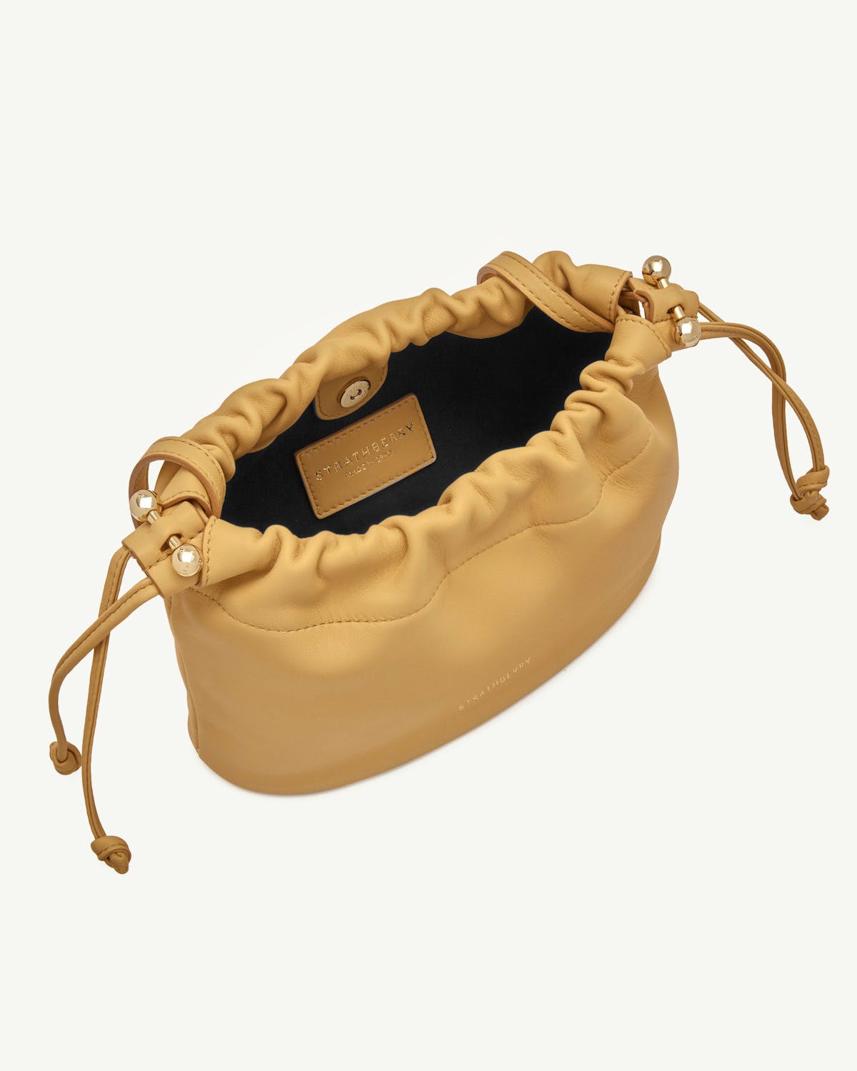 Brûlée Charlotte drawstring bag with visible Strathberry label and gold bead details.
