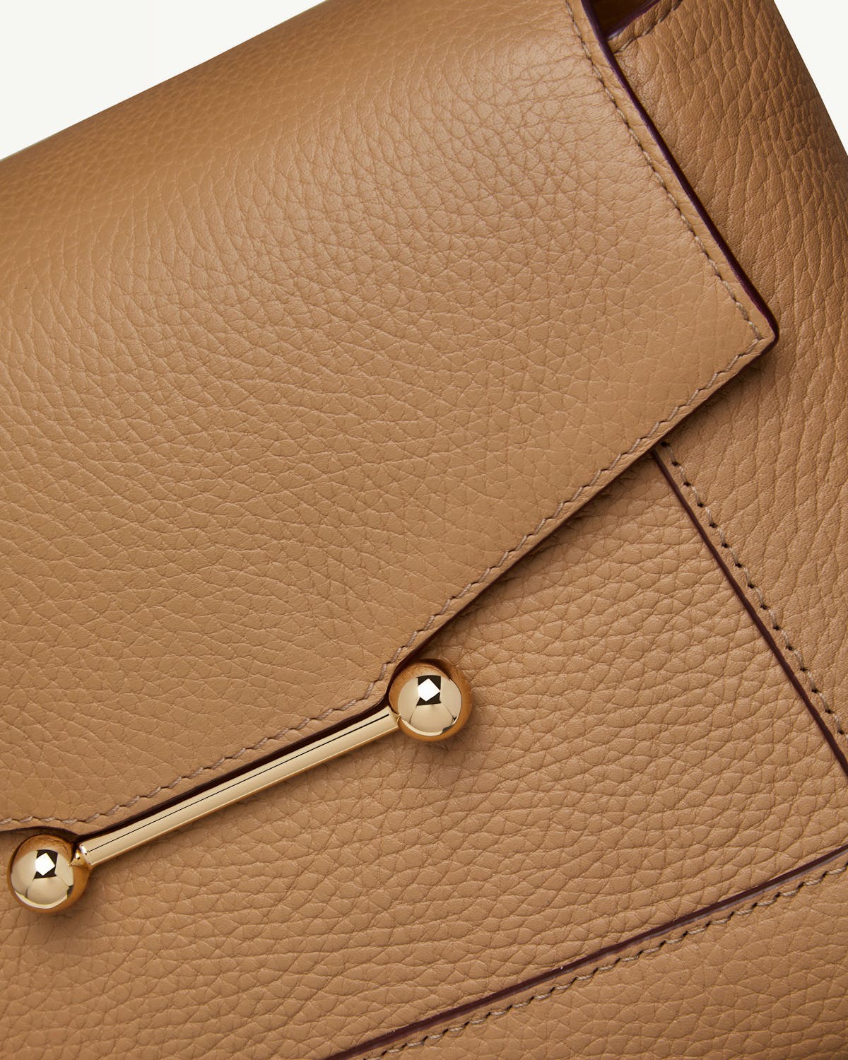 Close-up of caramel pebbled leather mosaic bag showing gold bar hardware.