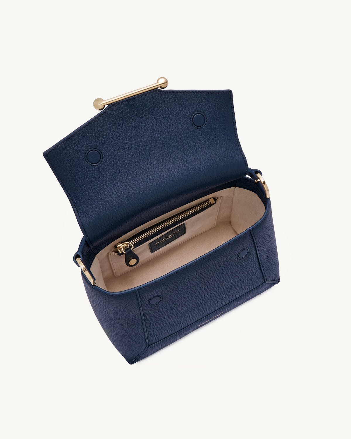 Navy mosaic bag open, beige lining, gold zip and bar closure visible.