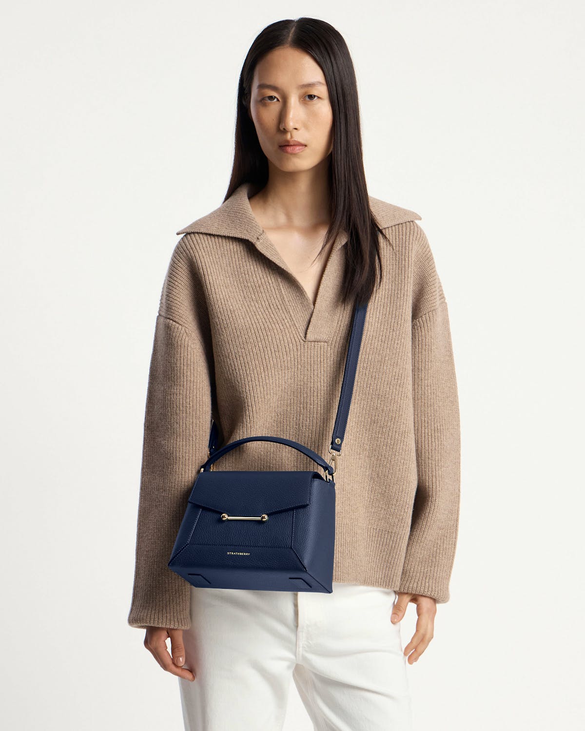 Model wearing navy Strathberry mosaic bag with top handle and gold hardware.