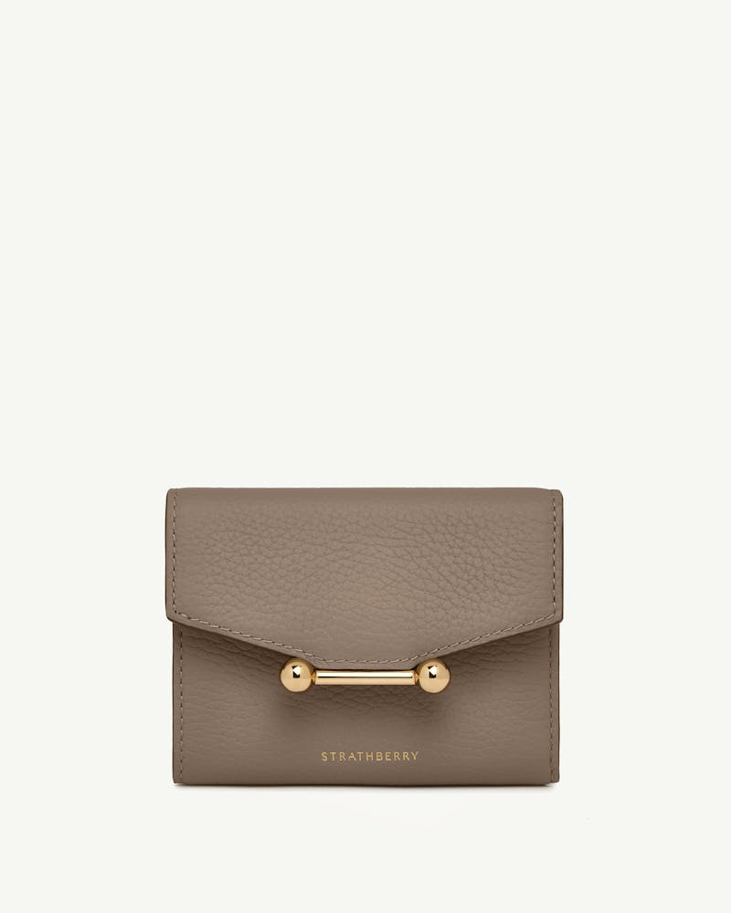 Taupe trifold leather wallet with gold bar closure and Strathberry logo.