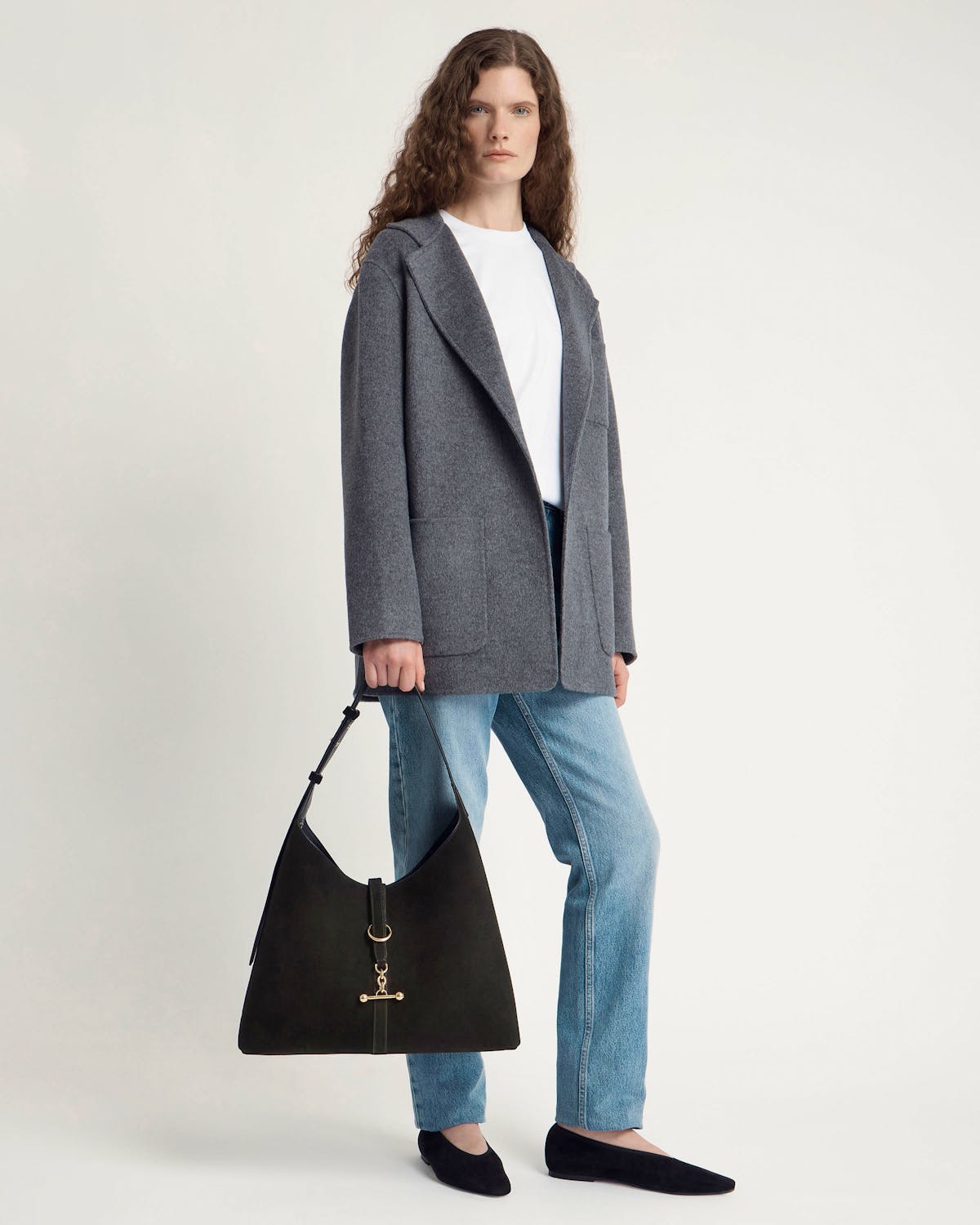 Model holding large black suede hobo bag with gold hardware
