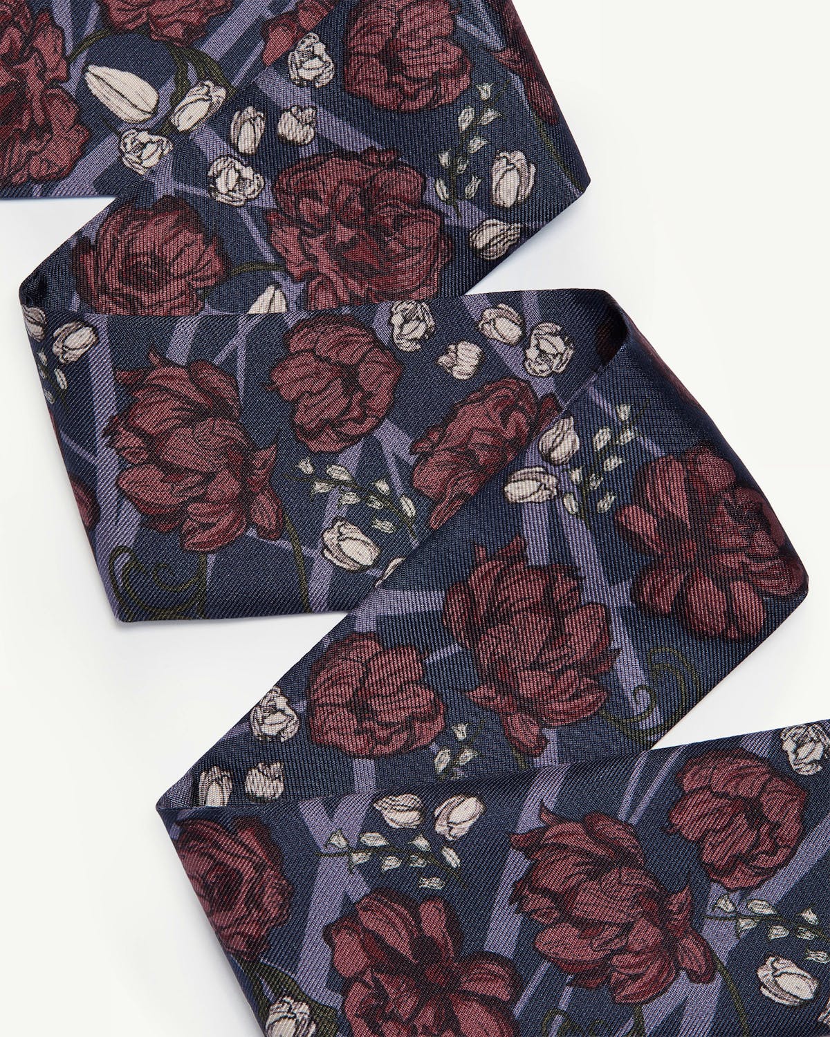 Silk skinny scarf with burgundy floral print on navy background.