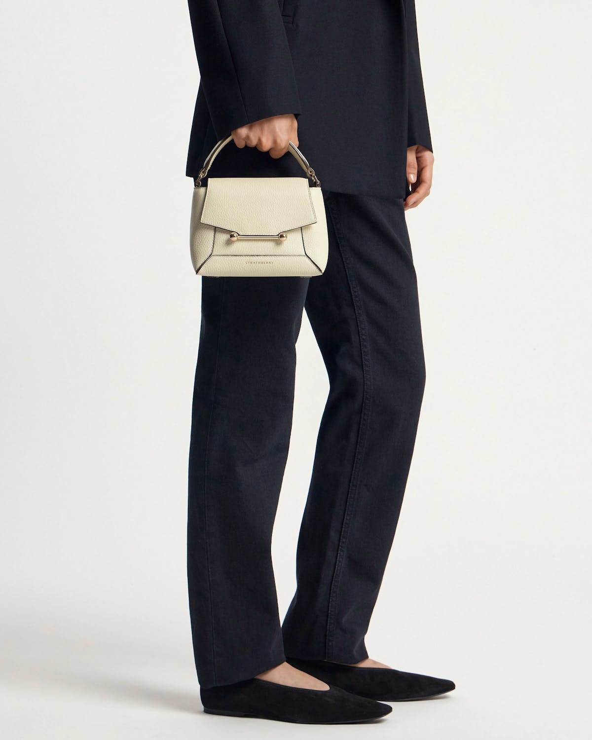 Model holding vanilla Mosaic Nano top-handle bag with gold bar fastening.