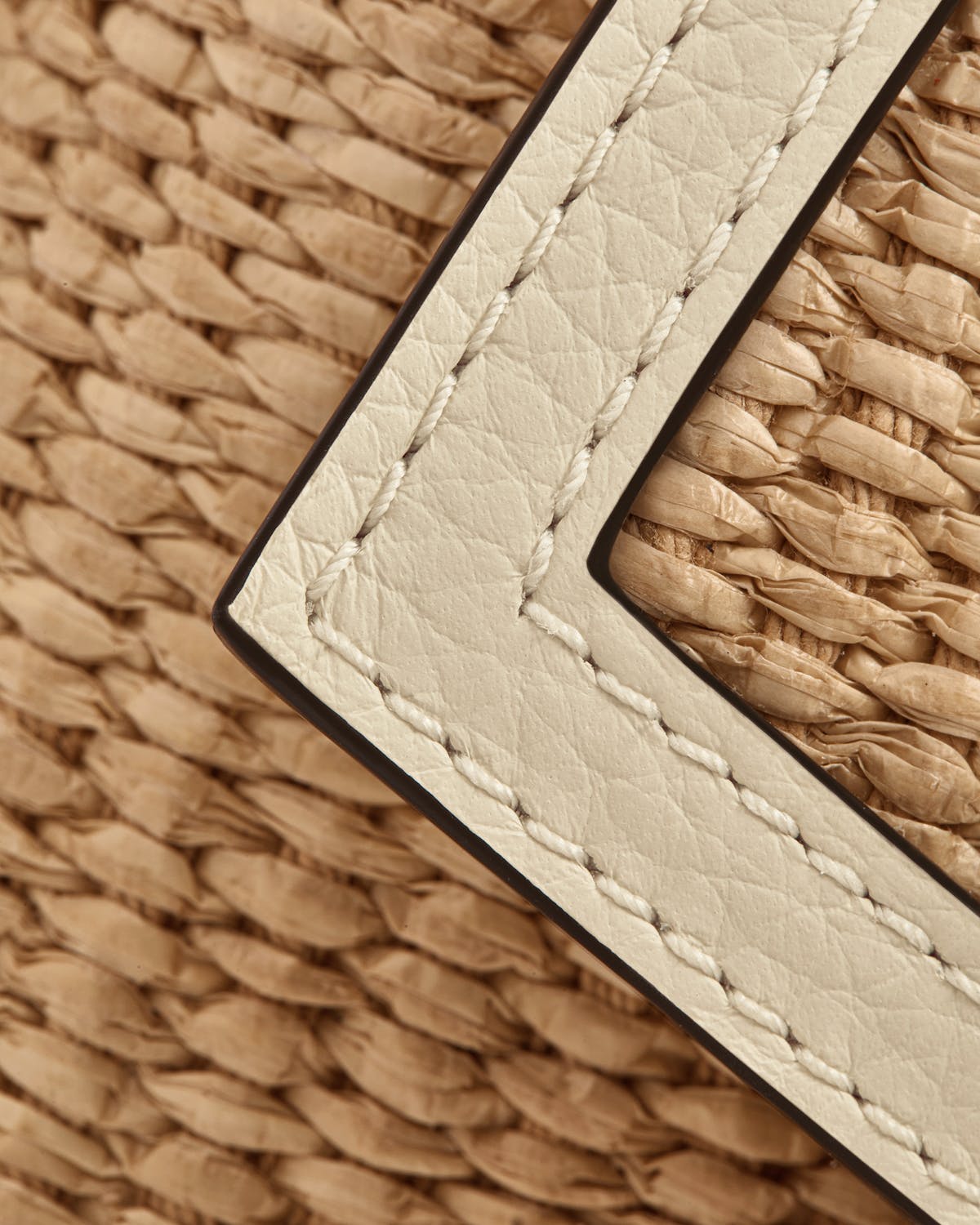 Vanilla leather trim with white stitching over natural raffia weave.