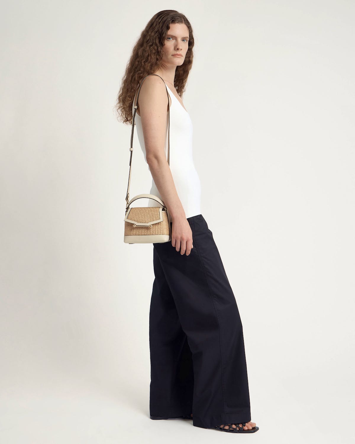 Model wearing vanilla and natural raffia Mosaic Nano bag at her side.