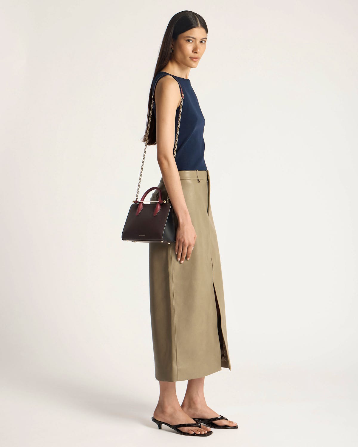 Model in navy top and khaki skirt holding espresso, oxblood and black mini tote