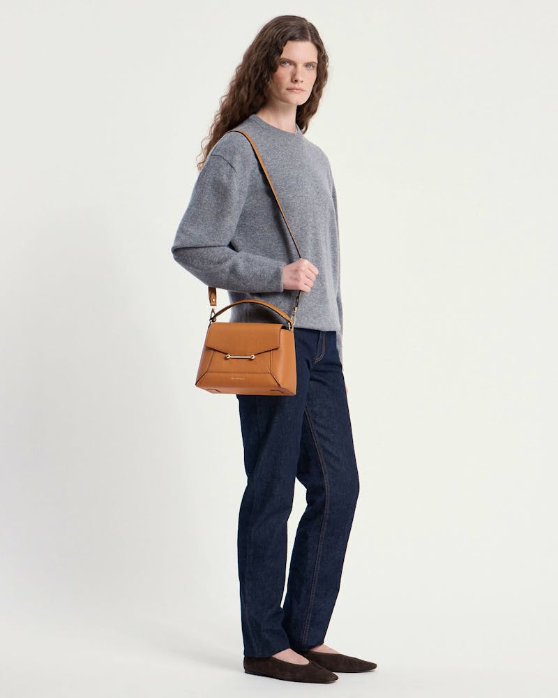 Model wearing a grey jumper and jeans carrying a honey mosaic bag over her shoulder.