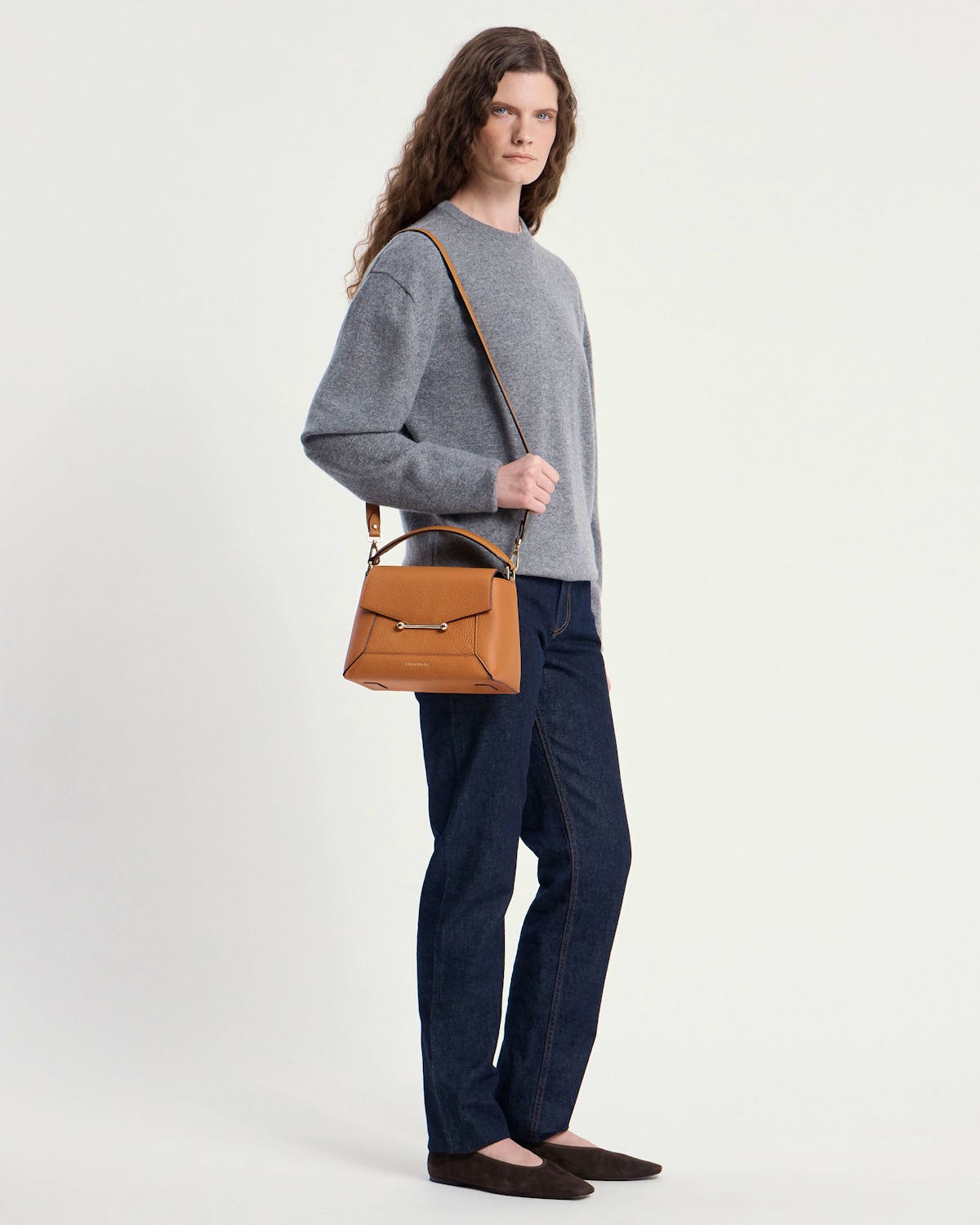 Model wearing a grey jumper and jeans carrying a honey mosaic bag over her shoulder.