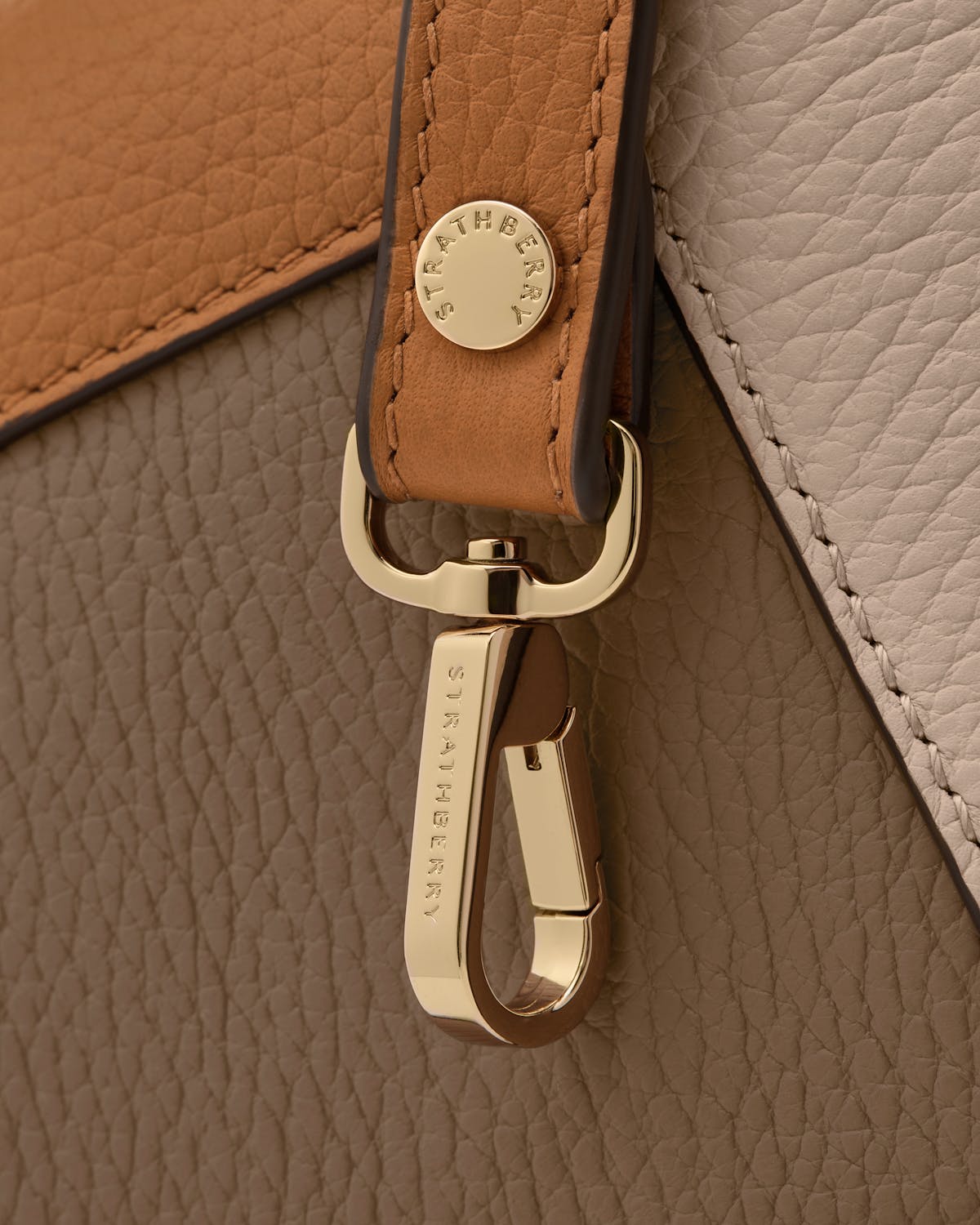 Gold clasp with Strathberry engraving on oat, honey and clay leather.