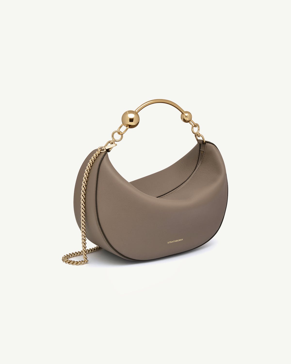Taupe crescent-shaped leather bag with gold chain and Strathberry logo.