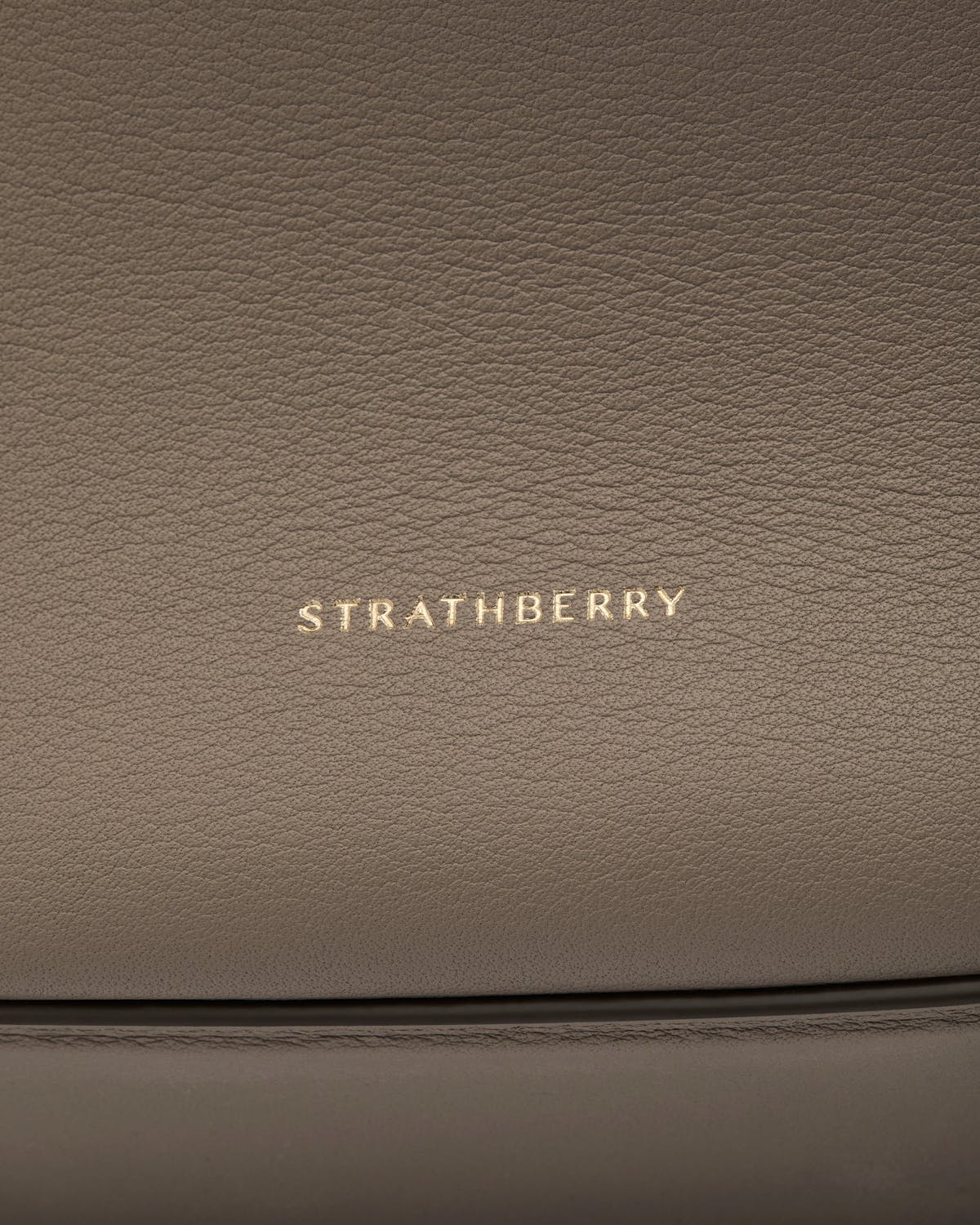 Taupe pebbled leather with gold Strathberry logo and stitched seam details.