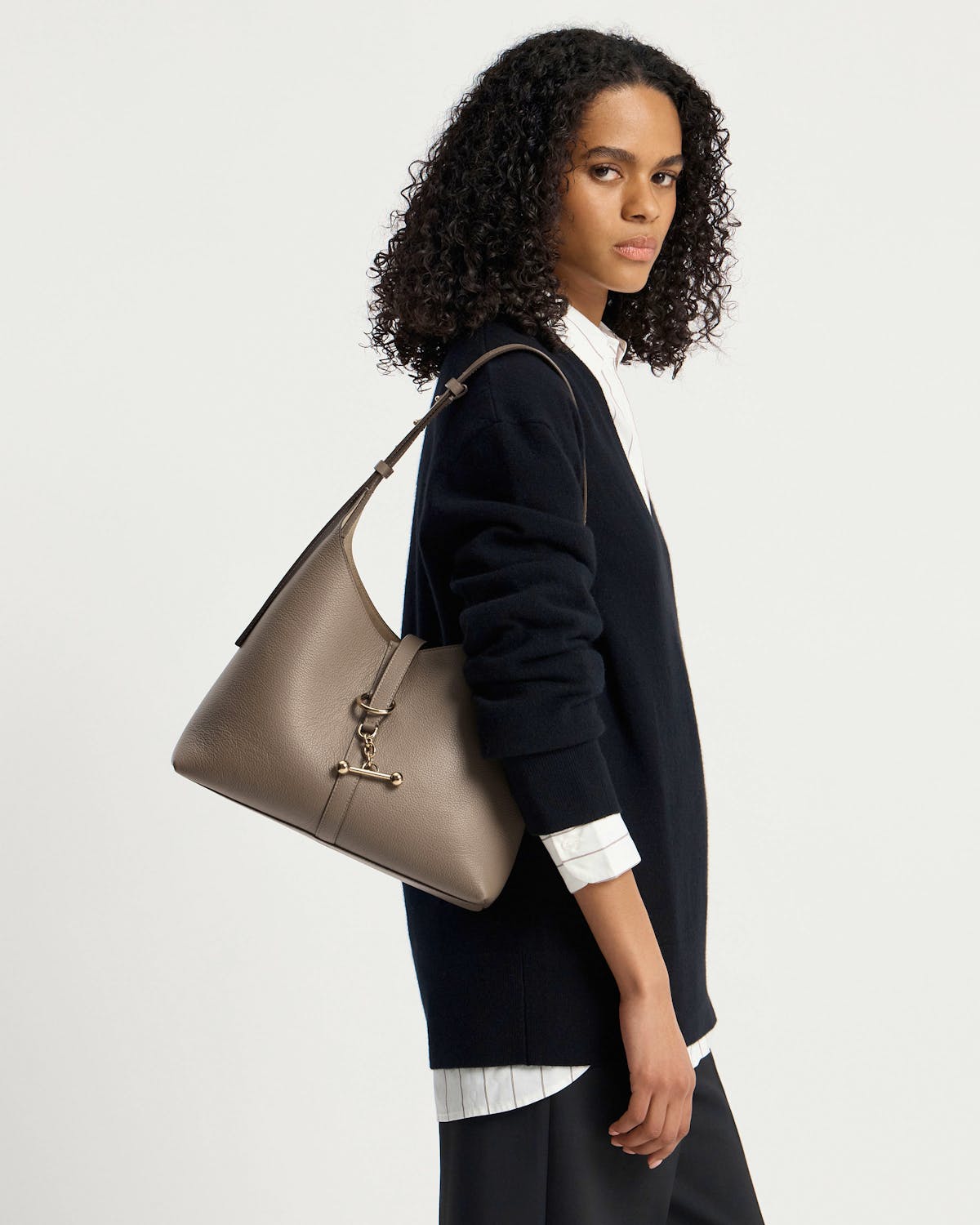 Woman wearing a black sweater carrying a taupe Kite Hobo shoulder bag.
