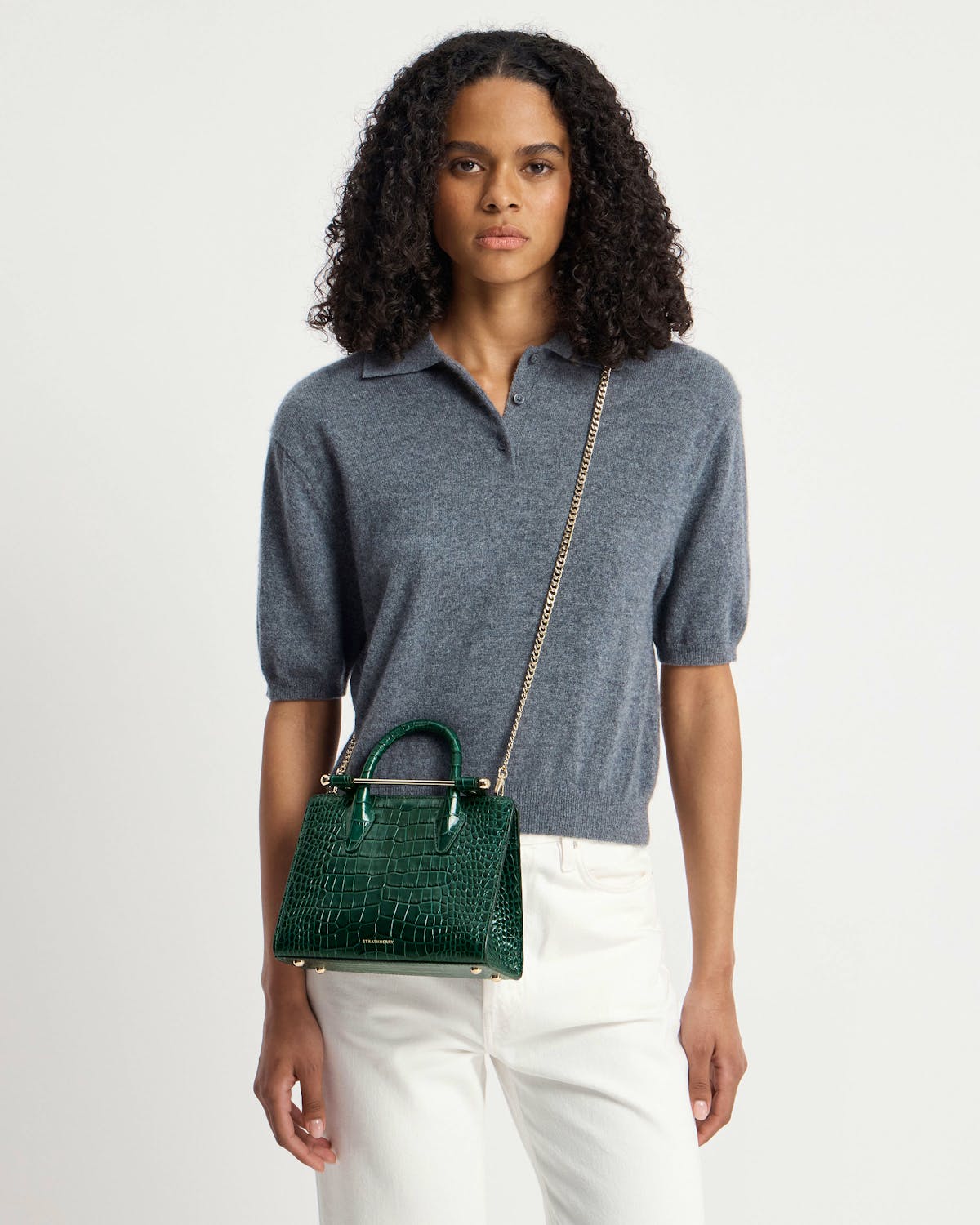 Strathberry green croc mini tote worn crossbody by model in grey top.